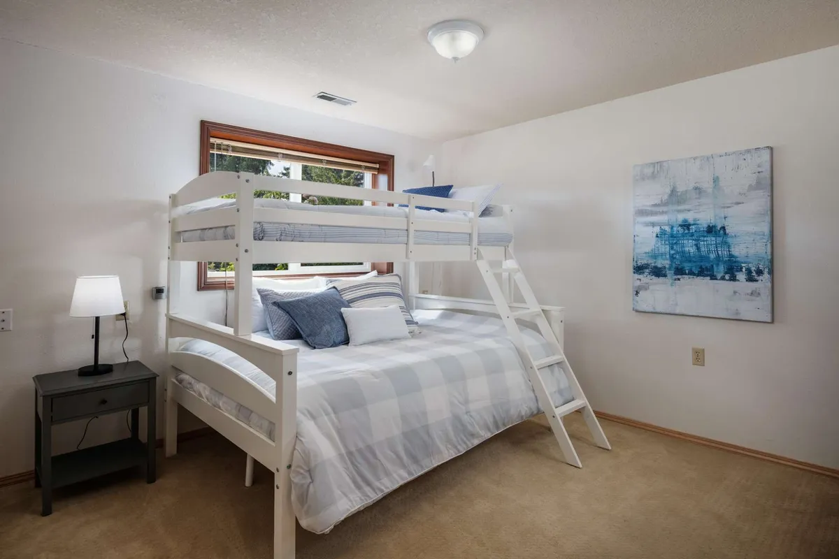 A children's bedroom featuring a cozy bunk bed, playful artwork, and a nightstand, all in a warm and inviting setting ideal for family stays. The space suggests fun sleepovers, quiet reading, and playful bonding moments.