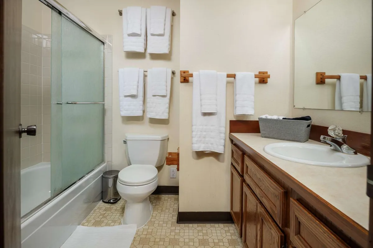 A contemporary bathroom with a vanity, sink, shower area, and towel rack. The space is bright, clean, and easily accessible—reflecting the practical amenities available to all guests.