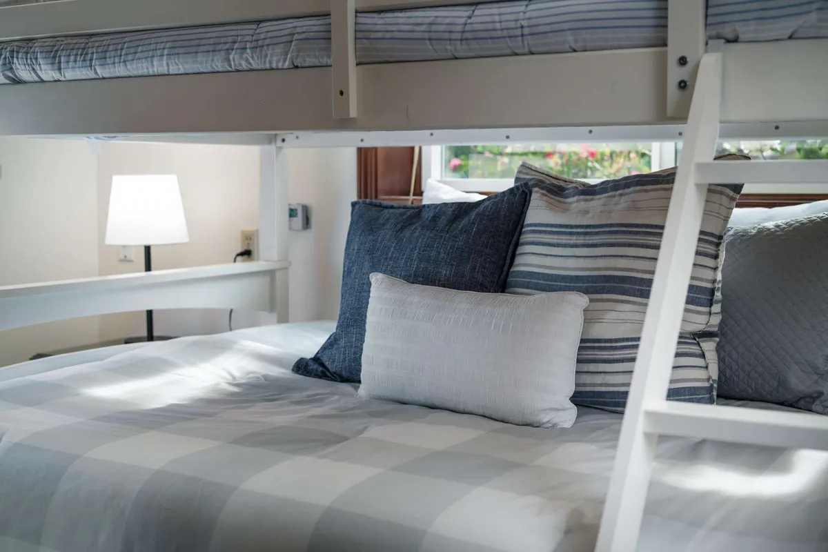 A cozy bunk bed setup with decorative pillows and a bedside lamp, offering a glimpse of comfortable sleeping arrangements suitable for families or groups. The inviting atmosphere suggests restful nights after days filled with adventure.