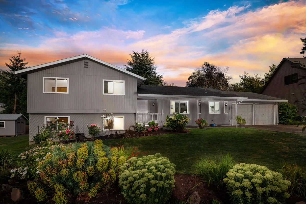 The image showcases the home's charming exterior, highlighted by vibrant front yard flowers, a lush, well-maintained lawn, and the inviting facade of the house. The scene suggests a peaceful, suburban setting perfect for relaxing outdoors, hosting family gatherings, or enjoying quiet evenings watching sunsets from the comfort of the front yard.